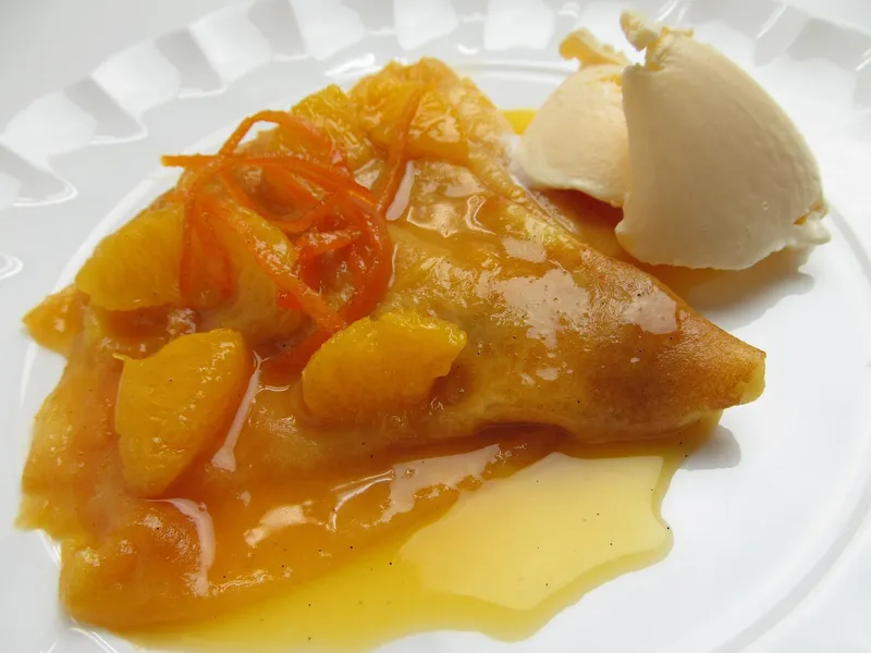 Crêpe Suzette mit Orangenfilets und Vanilleeis, flambiert serviert
